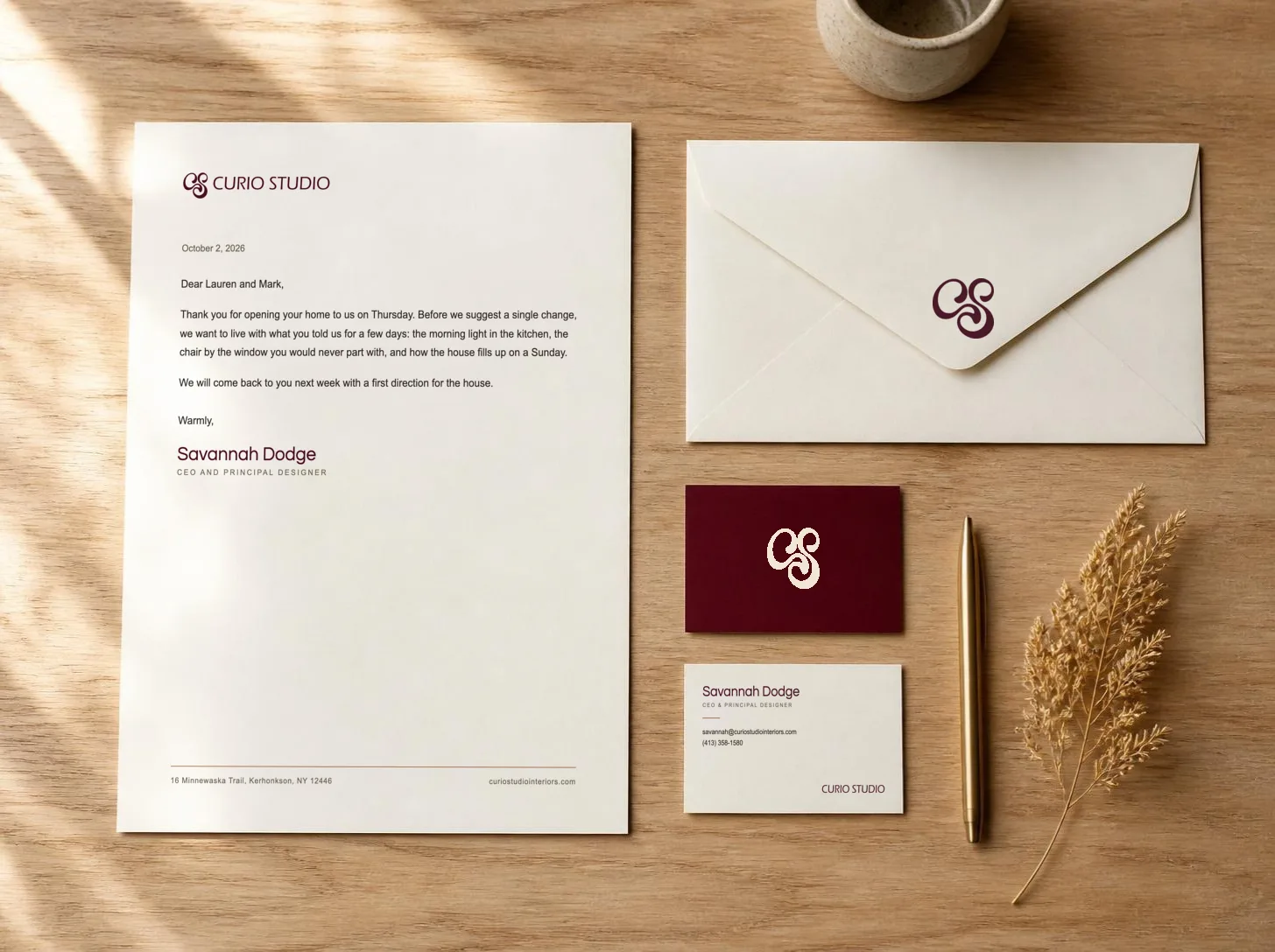Curio Studio letterhead with a letter from Savannah Dodge, an envelope and two business cards on an oak table
