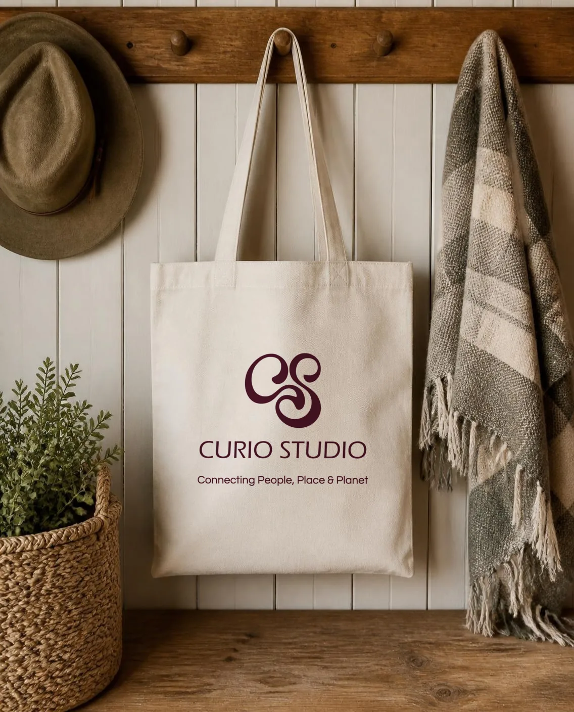 A canvas tote printed with the Curio monogram, wordmark and tagline on a peg rail